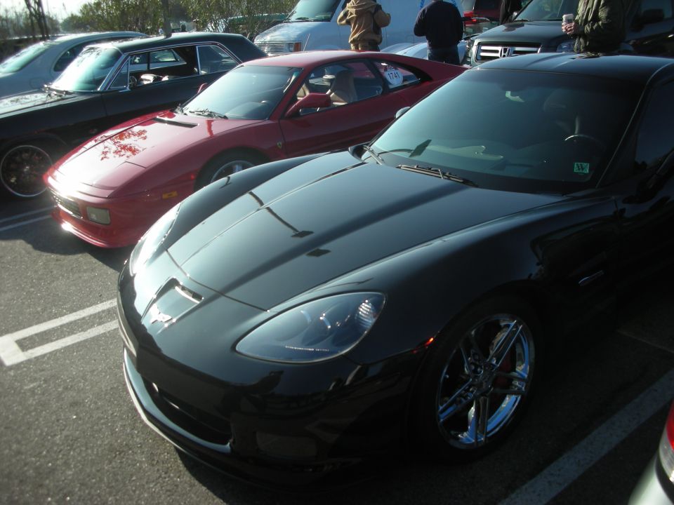 Black C6 Corvette parked beside a red sports car at a show