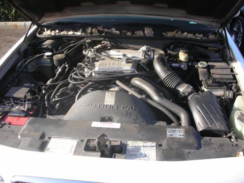 1998 Ford Crown Victoria - The engine bay of a 1998 Ford Crown Victoria, showing the V8 engine and various components, including a 'Caution Fan' warning label.
