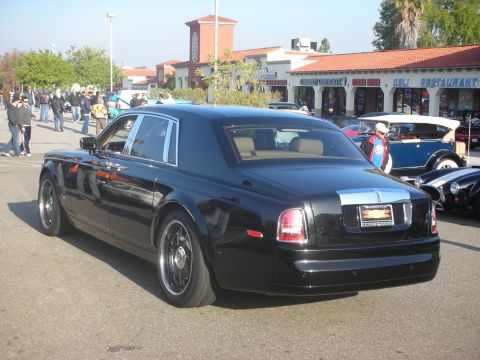 1998 Ford Crown Victoria - A black Rolls-Royce Phantom is parked at an outdoor gathering with other vehicles and people.