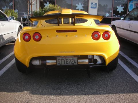 1998 Ford Crown Victoria - Rear view of a yellow Lotus Exige parked next to other vehicles.