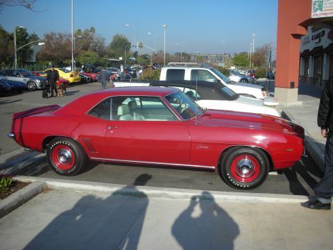 1998 Ford Crown Victoria - A red 1969 Chevrolet Camaro is parked at a car meet with other vehicles visible.