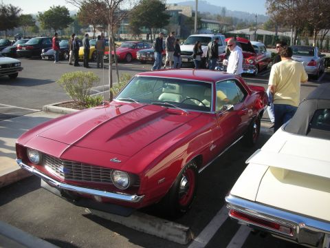 1998 Ford Crown Victoria - Red 1969 Chevrolet Camaro at a car meet. Other vehicles and people are in the background.