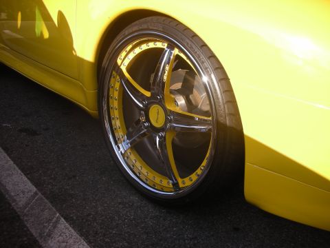 1998 Ford Crown Victoria - A close-up view of a yellow car's custom wheel, chrome and bright yellow accents on the spokes and rim.