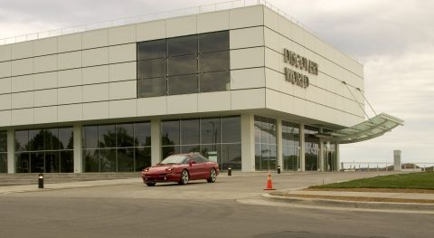 1993 Ford Probe - A red 1993 Ford Probe is captured in a three-quarter front view as it drives past the Discover World building.