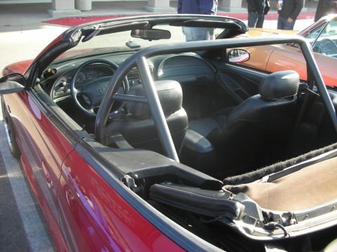 1998 Ford Crown Victoria - Interior view of a red convertible with a roll bar, parked next to another vehicle.
