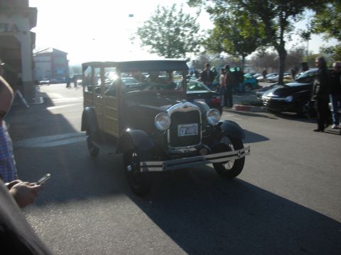 1998 Ford Crown Victoria - A vintage 1929 Ford Model A woody wagon is seen at a car meet, its distinctive body style and license plate clearly visible.