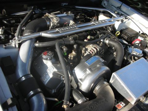 1998 Ford Crown Victoria - Close-up of a modified engine bay a prominent supercharger and custom intake system.