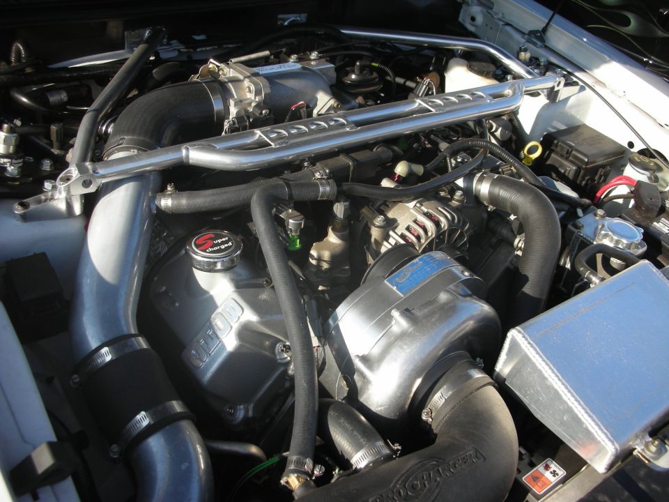 Engine bay with supercharger, strut brace, and polished intake piping