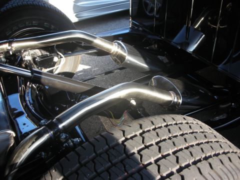 1998 Ford Crown Victoria - A close-up view of the undercarriage of a vehicle, focusing on its exhaust pipes and a tire.