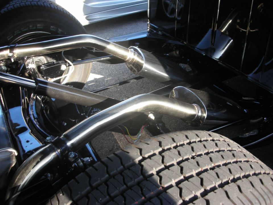 Underside chassis view of a hot rod showing polished exhaust pipes