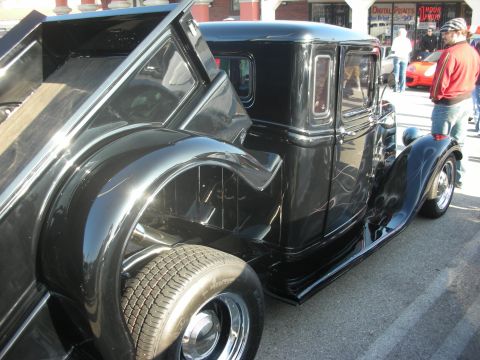 1998 Ford Crown Victoria - A black hot rod truck with custom flame graphics is parked outdoors, showing its open bed and classic styling.