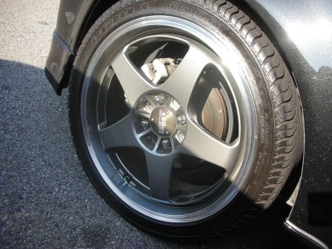 1998 Ford Crown Victoria - A close-up shot focuses on a custom wheel and tire assembly, highlighting the brake caliper behind the spokes.