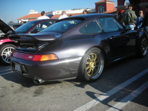1998 Ford Crown Victoria - A dark purple Porsche 911 is parked in a lot next to other vehicles.