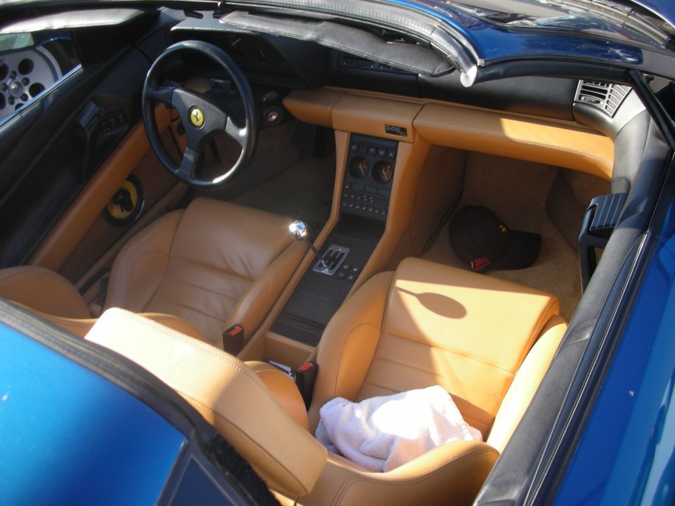 Tan leather interior of a blue Ferrari with yellow steering hub