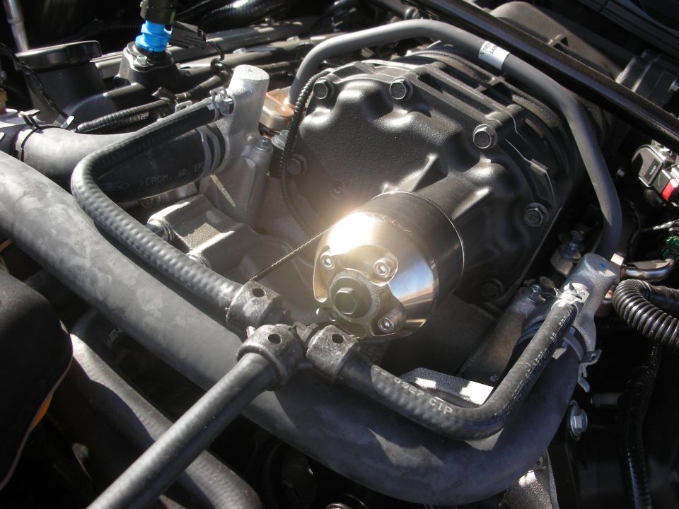Close-up of a black engine cam cover with a polished oil cap under sunlight