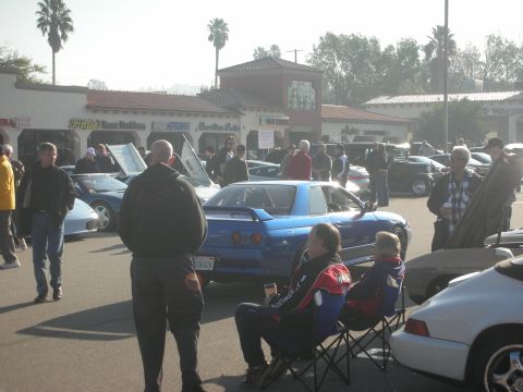 1998 Ford Crown Victoria - Attendees socialize around various vehicles at a daytime car gathering.