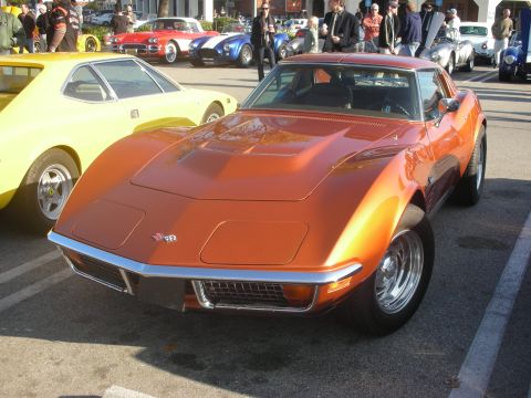 1998 Ford Crown Victoria - An orange 1969 Chevrolet Corvette is parked at a car meet with other vehicles in the background.