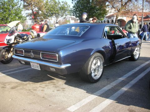 1998 Ford Crown Victoria - A dark blue 1967 Chevrolet Camaro is parked at a car meet, showing off its classic muscle car styling and custom wheels.