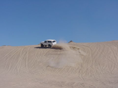 1992 Ford Bronco - White 1992 Ford Bronco driving on a sand dune.