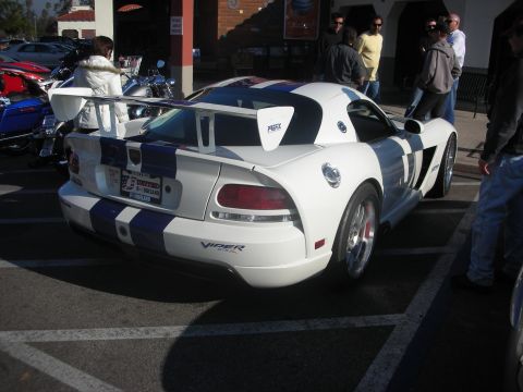 1998 Ford Crown Victoria - A white and blue striped Dodge Viper is parked in a lot, a prominent rear spoiler and racing stripes.