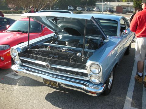 1998 Ford Crown Victoria - A light blue 1967 AMC Rambler American coupe is parked with its hood open, revealing the engine bay.