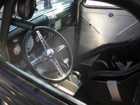 1998 Ford Crown Victoria - The interior of a modified vehicle features a custom steering wheel, racing seat, and various gauges.