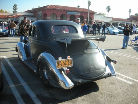 1998 Ford Crown Victoria - A custom hot rod coupe with a spoiler and chrome accents is parked at a car meet. Other vehicles and people are visible in the background.