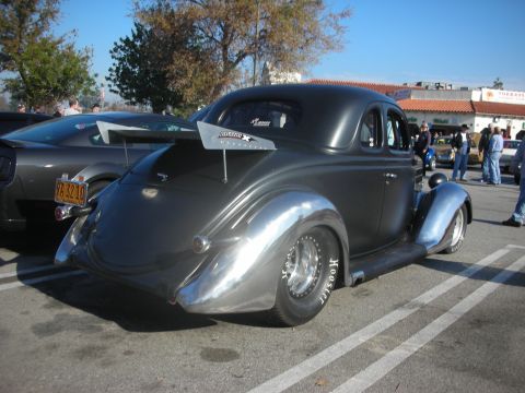 1998 Ford Crown Victoria - Hot rod coupe with polished fenders and drag slicks parked next to another vehicle.