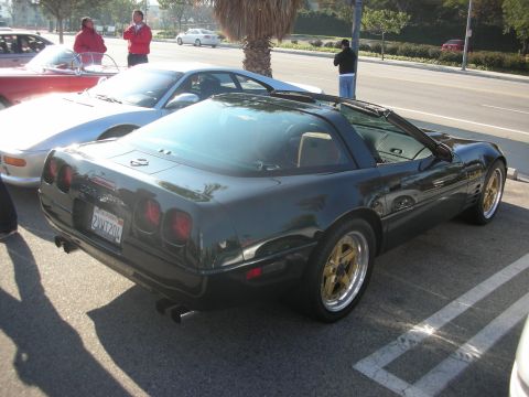 1998 Ford Crown Victoria - A dark green Chevrolet Corvette C4 is parked next to other vehicles, with a palm tree overhead.