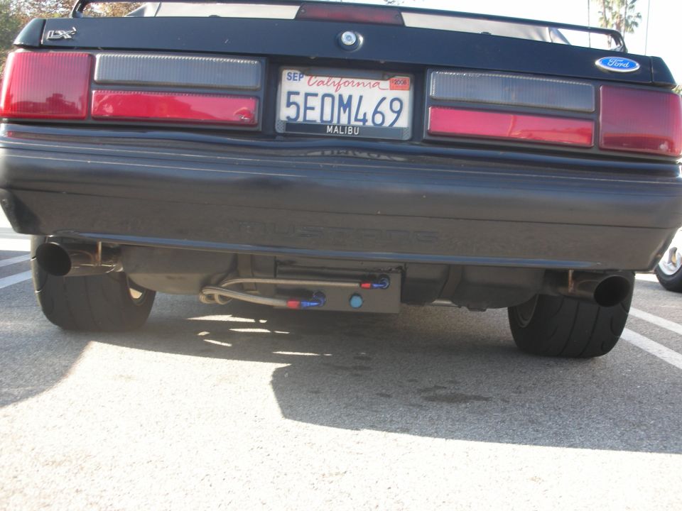 Rear bumper of a black Fox-body Ford Mustang LX with California plate