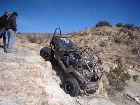 1989 Ford Bronco - A custom buggy navigates a steep, rocky incline under a clear blue sky.