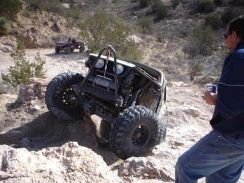 1989 Ford Bronco - This heavily modified off-road buggy is navigating a rocky incline with another vehicle in the background.