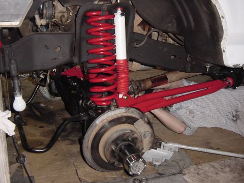 1992 Ford Bronco - Custom red suspension components, including coilover shocks and control arms, are visible on a vehicle's undercarriage.