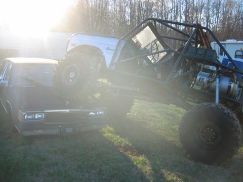 1992 Ford Mustang - Custom off-road buggy is perched on top of a sedan in a grassy area.