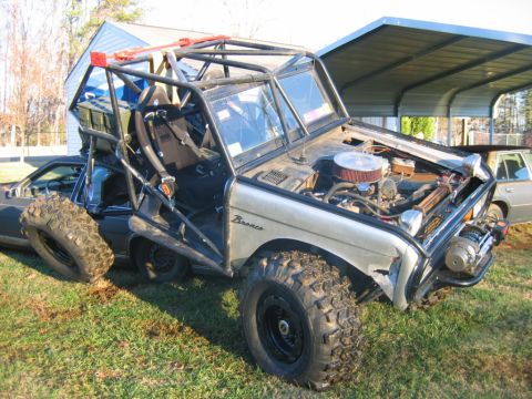 1992 Ford Mustang - Modified Ford Bronco with extensive roll cage and off-road modifications is parked on a grassy area.