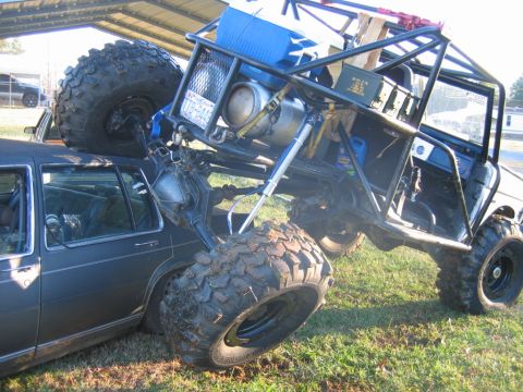 1992 Ford Mustang - An extreme off-road vehicle is perched atop a sedan, a dramatic scene of vehicular interaction.