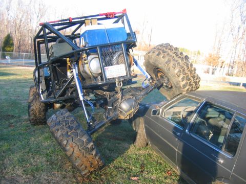 1992 Ford Mustang - An extreme off-road buggy is positioned on top of a sedan, crushing its roof.