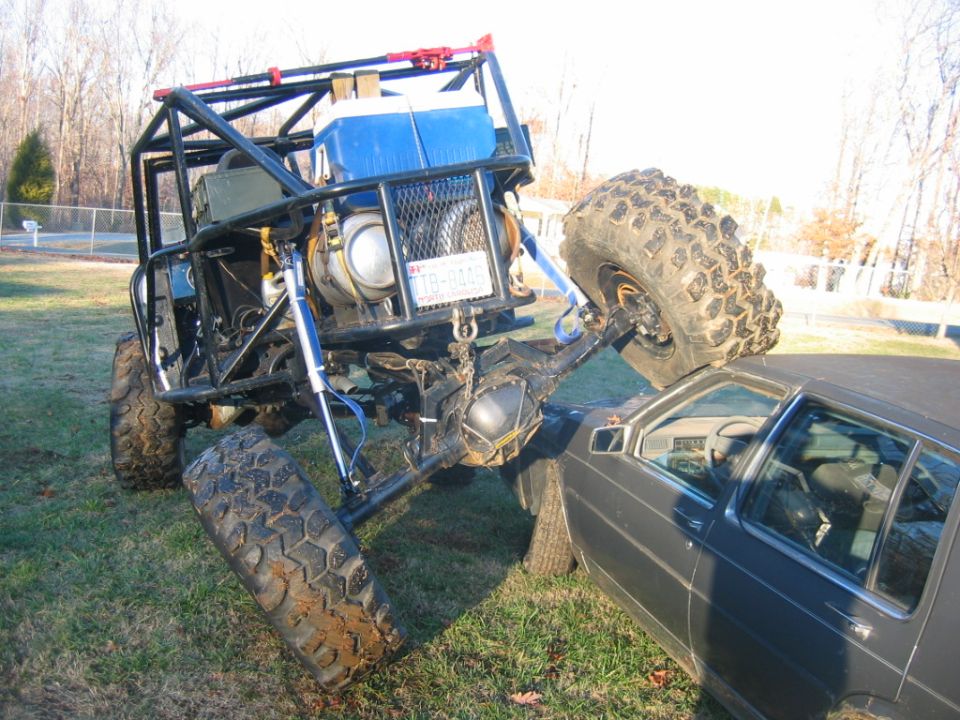 Off-road buggy crushing a sedan's roof, rear view