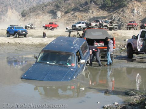 1987 Suzuki Samurai - Several off-road vehicles gathered, with one blue SUV stuck in a water obstacle.