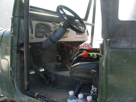 1987 Suzuki Samurai - The interior of a green off-road vehicle shows a diamond plate dashboard and a roll cage, suggesting it is modified for use.