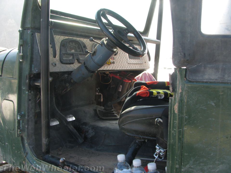 Interior of a green off-road vehicle with a diamond plate dashboard and roll cage