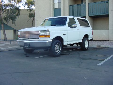 1992 Ford Bronco - A white 1992 Ford Bronco is parked in an asphalt lot with a building in the background.