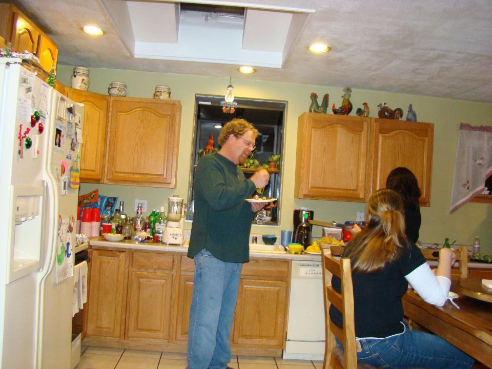Kitchen scene with people gathered around a counter and table