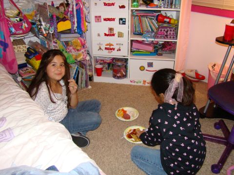 1989 Ford Bronco - Two young girls are sitting on the floor in a bedroom, eating snacks from paper plates.