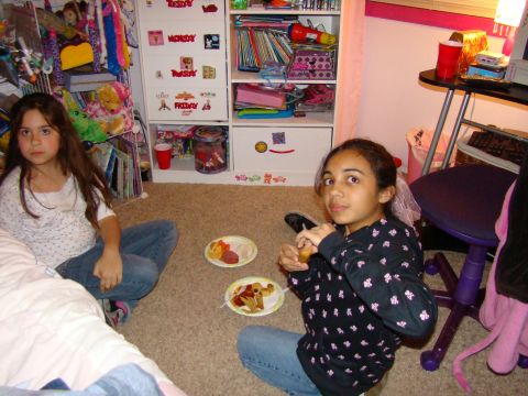 1989 Ford Bronco - Two young girls are enjoying snacks in a bedroom, surrounded by toys and books.