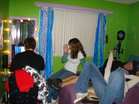 1989 Ford Bronco - A group of young adults are socializing in a room with vibrant green walls and colorful curtains.