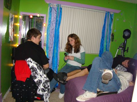 1989 Ford Bronco - Three young people are in a bedroom, one is looking at a phone while others relax on the bed.