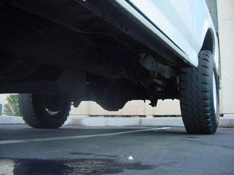 1992 Ford Bronco - Low angle shot of a truck's undercarriage and rear wheel.