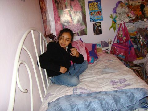 1989 Ford Bronco - A young girl sits on her bed, surrounded by posters and stuffed animals.