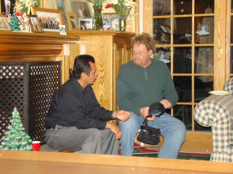 1989 Ford Bronco - Two men converse in a room decorated for the holidays, with a fireplace and Christmas tree visible.